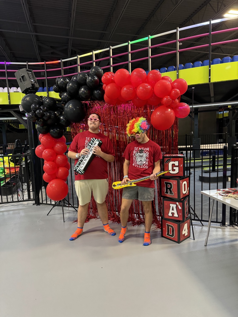 Graduates at the photo booth under a red and black balloon arch